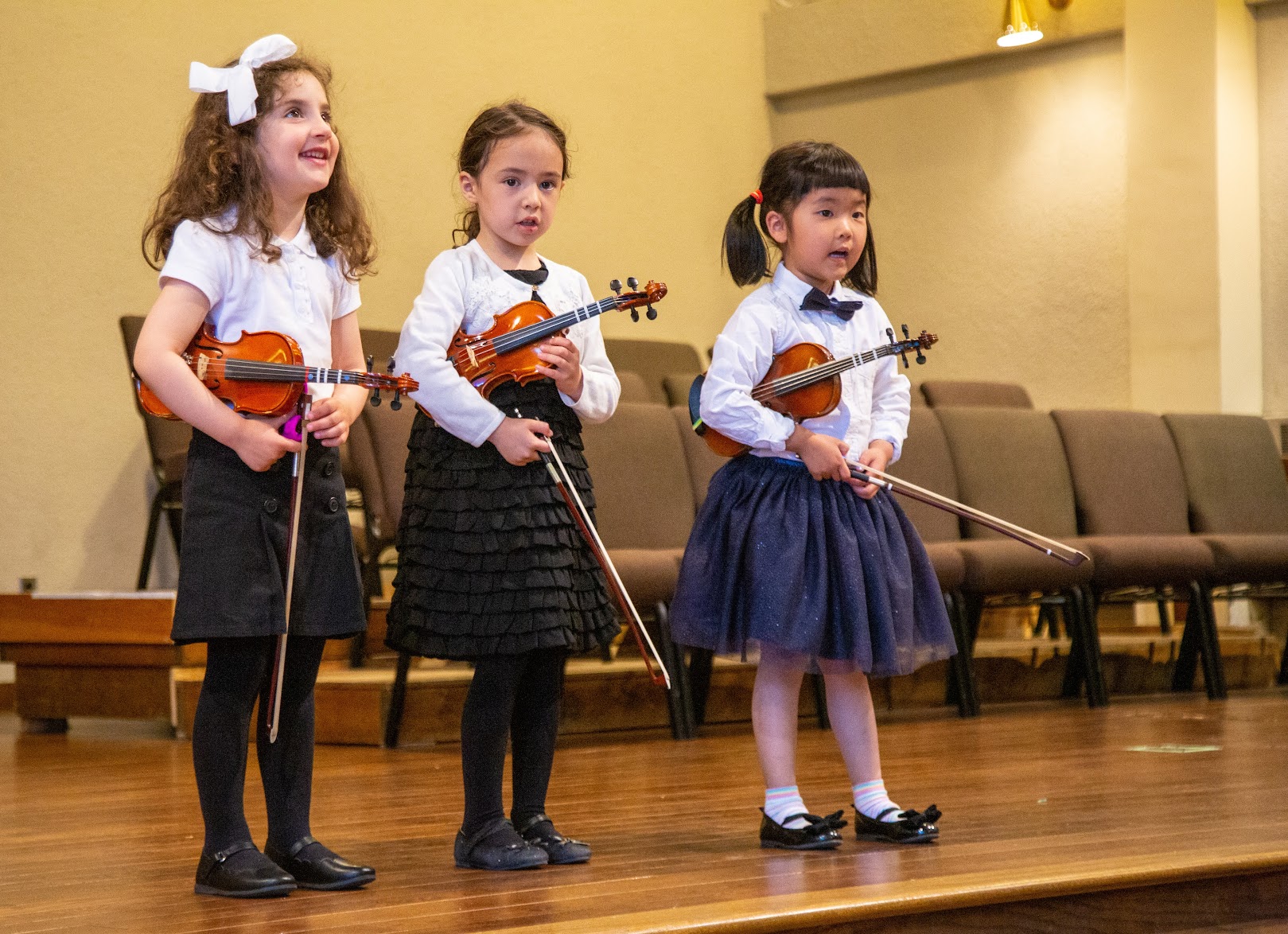 Three young violinists in rest position